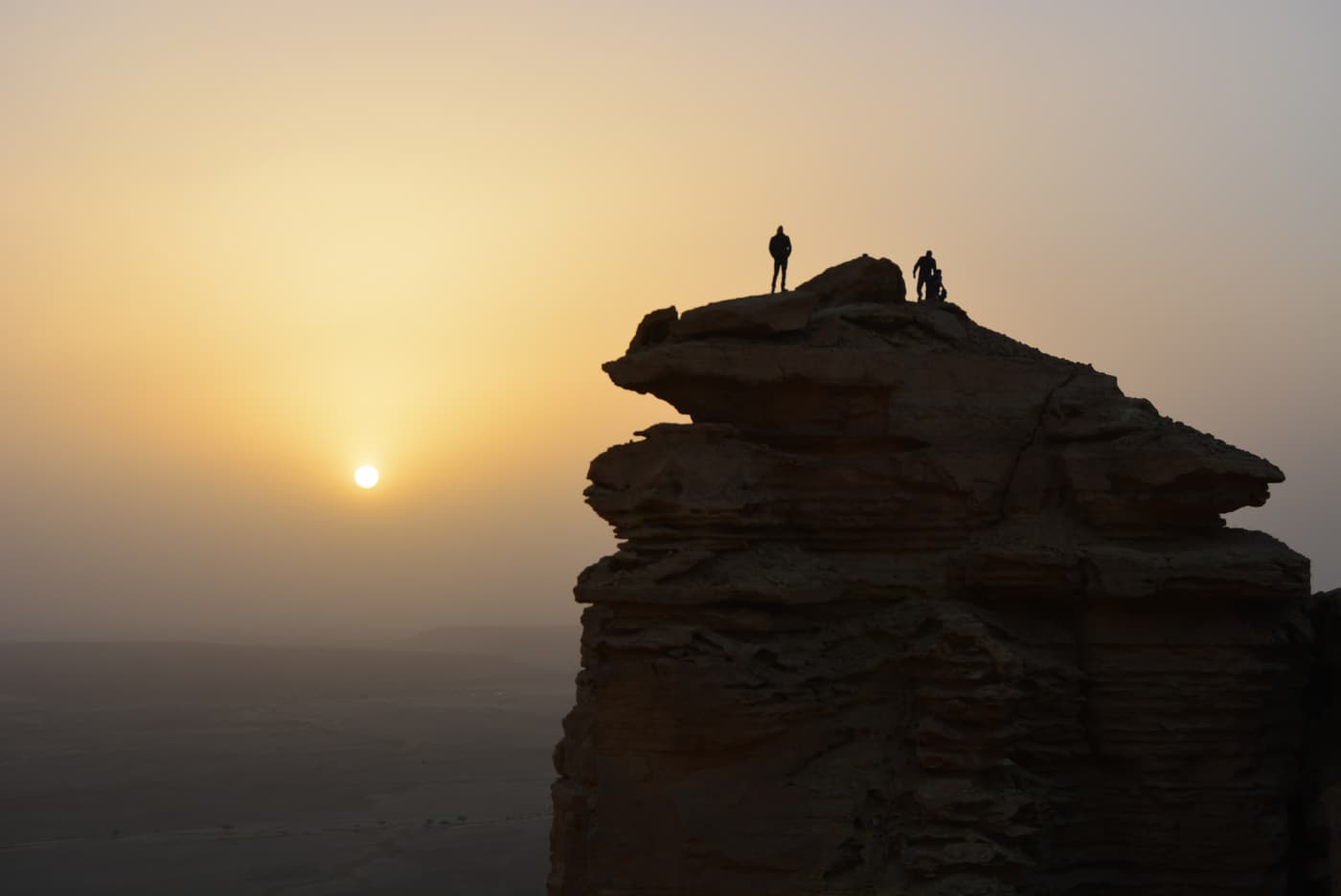 A lone figure on a rock pinnacle at the Edge of the World at sunset