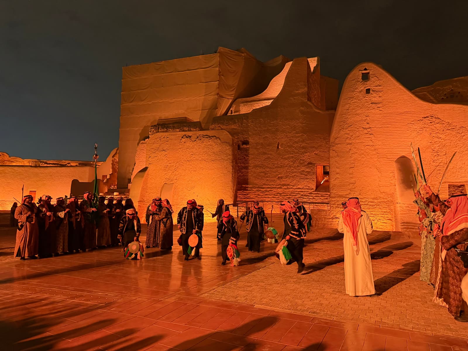 Performers of the Najdi sword dance in front of the floodlit walls of At-Turaif