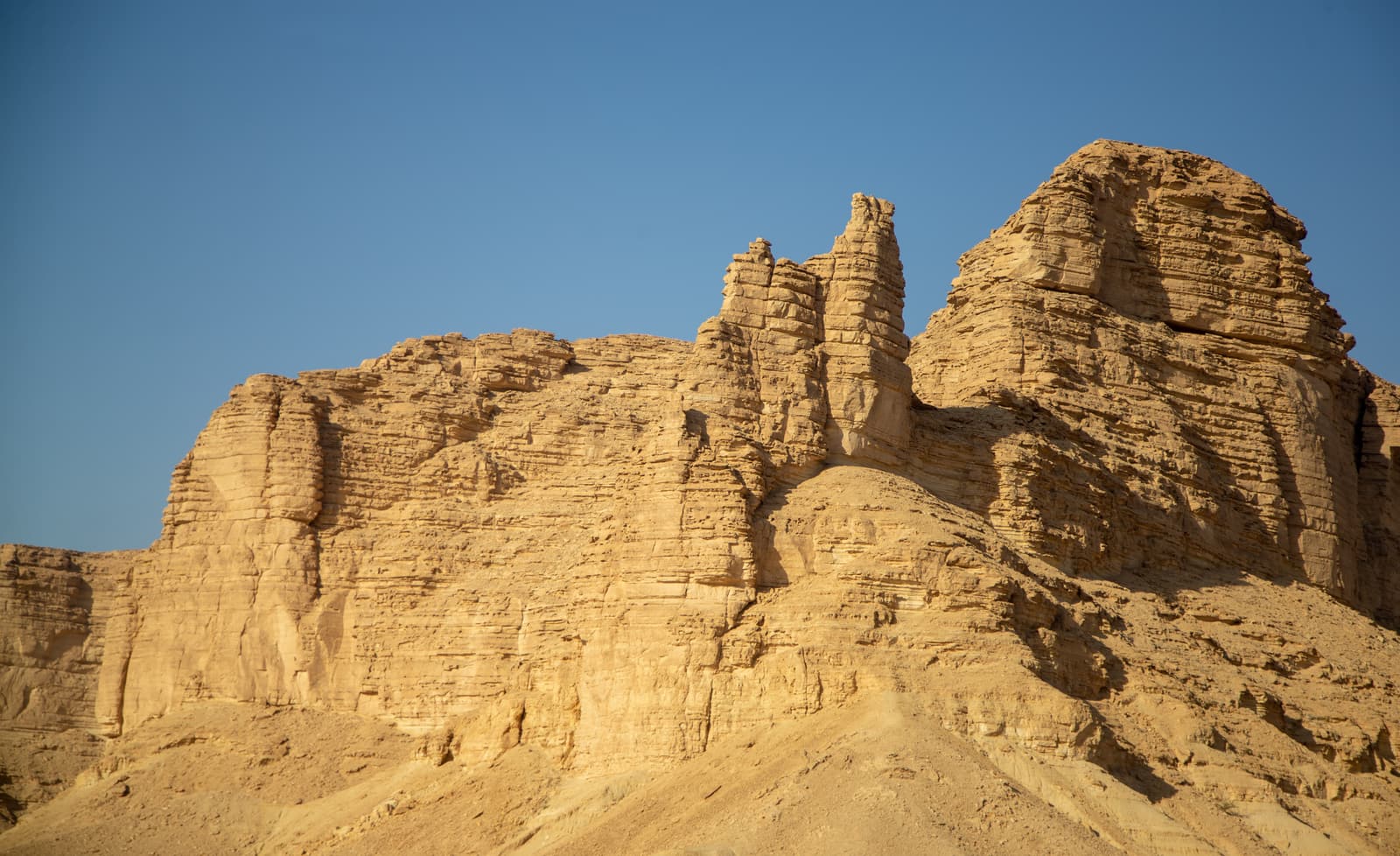Weathered rock towers of the Tuwaiq escarpment under a blue sky