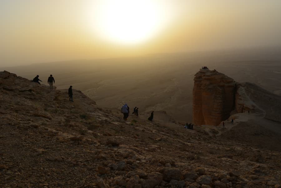 Hikers on the rim of the Edge of the World cliffs at sunset