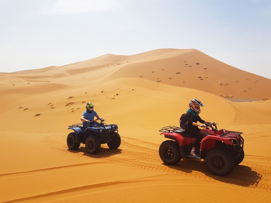 Riders on quad bikes among sand dunes